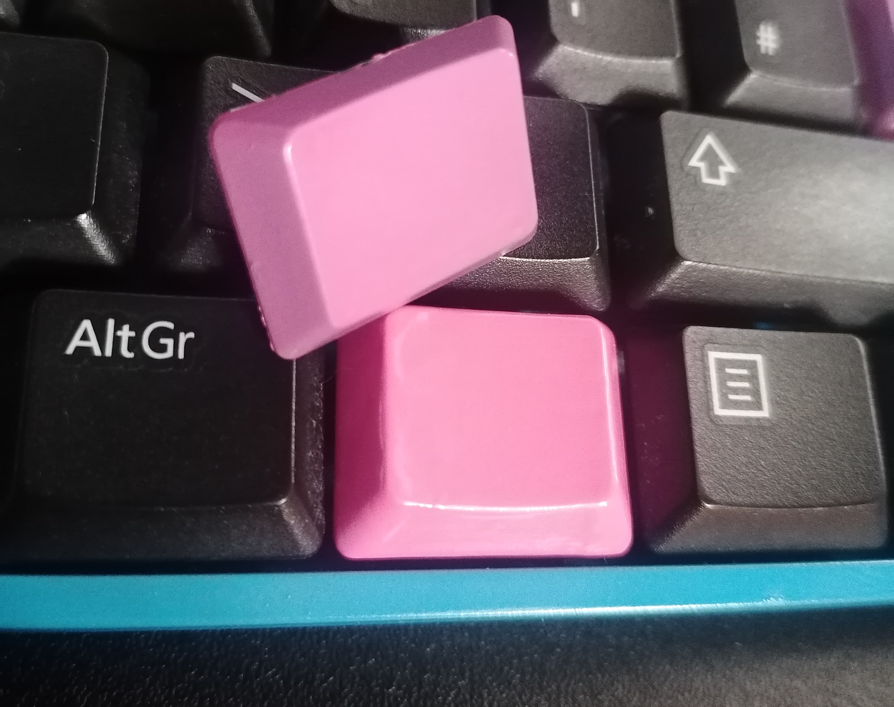 Two pink keys. One more vibrant with faint brushmarks is the varnish. 
