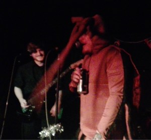ducking punches as papa roach. guitarist in the background is smiling at the lead singer dressed as a roach. he is holding a can of monster engery
