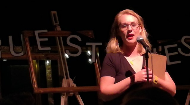 Photo of the host in front of a banner reading true stories live